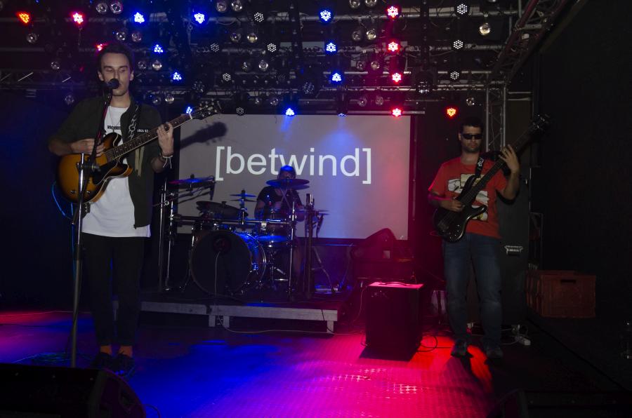 Koncert kapely Betwind na Melodce v Brně, modré a červené světlo, Michal zpívá, Zbyněk po pravé straně, Lukáš v pozadí, září 2019